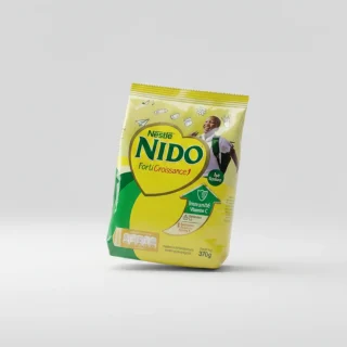 Une famille africaine heureuse prenant son petit-déjeuner avec un sachet de lait NIDO FortiCroissance sur la table.