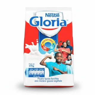 Sachet de lait Gloria avec une tasse de lait chaud fumant et de la poudre de lait sur une table.