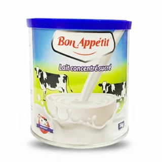 Boîte de lait concentré sucré Bon Appétit 1kg avec une main versant du lait onctueux sur un bol de couscous fumant.