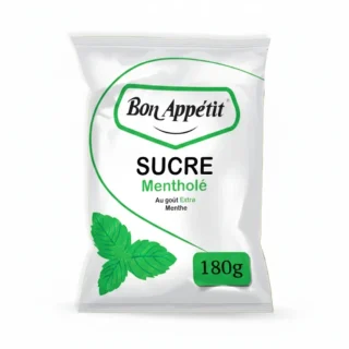 Sachet de sucre mentholé Bon Appétit 180g posé sur une table en bois à côté d'un verre de thé à Kolda.